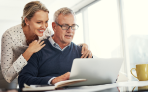 Happy, smiling pensioners review their finances on a laptop computer.