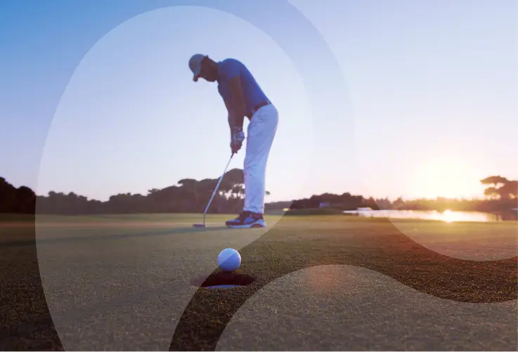 A golfer focusing on putting a ball into the hole at sunset, with the sun casting a warm glow over the course, demonstrating precision and dedication in the sport of golf.