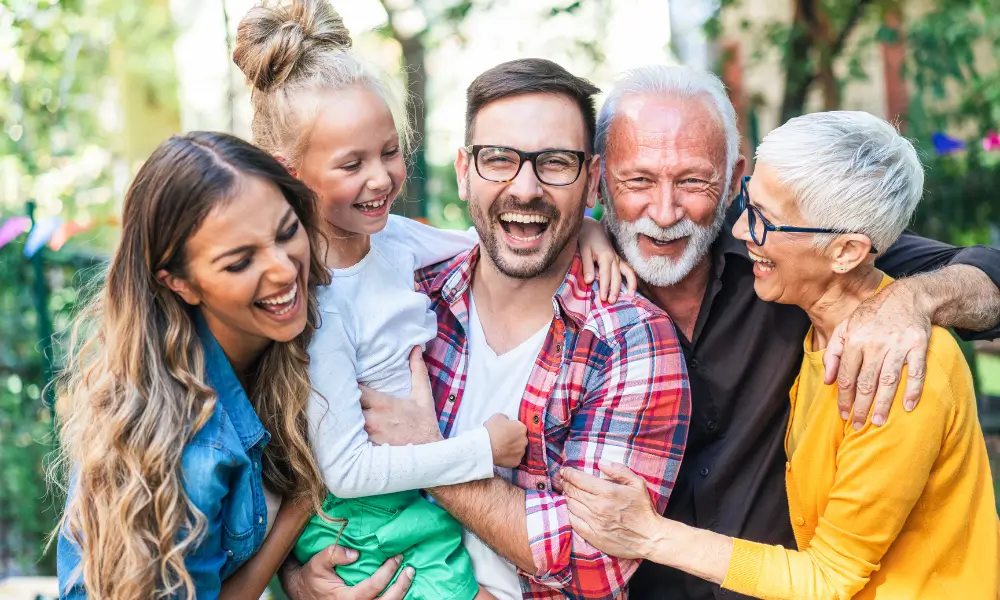 Young family with grandparents laughing and smiling while having a group photo.